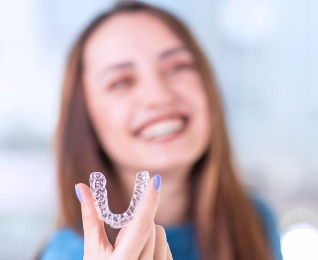 Woman smiling and holding her clear aligners