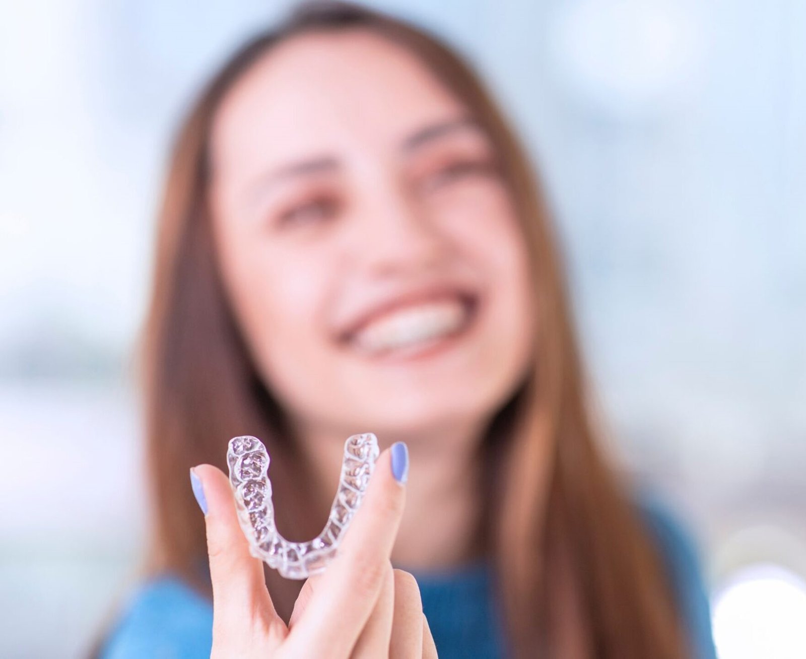 Woman smiling and holding her clear aligners
